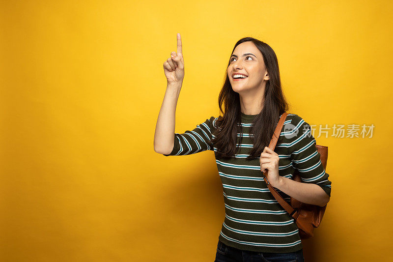 Portrait of female college student on yellow background stock photo